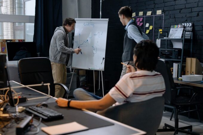 Startup ekibinin beyaz tahta üzerinde stratejiyi gözden geçirdiği toplantı