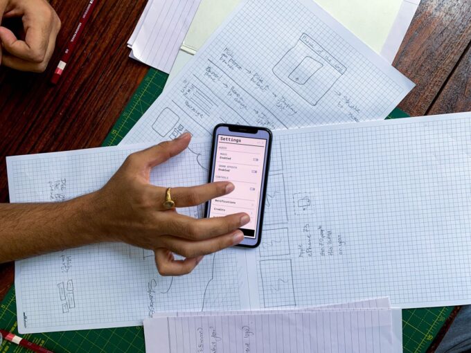 App design sketches and a smartphone on a desk